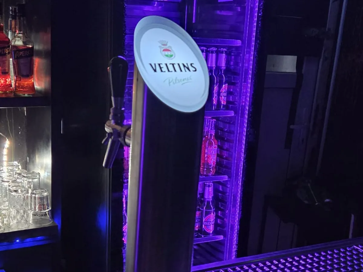 Veltins-Zapfsäule unter violettem Licht in einer Bar